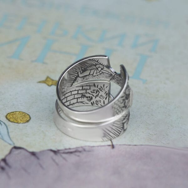Ring "Der Fuchs und der kleine Prinz" mit detaillierter Innengravur auf dem Hintergrund des Buches.