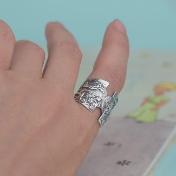 Ring "Der Fuchs und der kleine Prinz" auf dem Arm, der ein künstlerisches Relief mit dem kleinen Prinzen und Rosen zeigt.